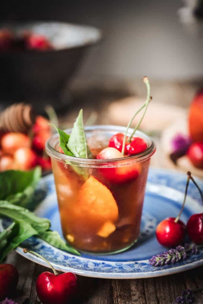 side view of bourbon peach smash cocktail on wood table