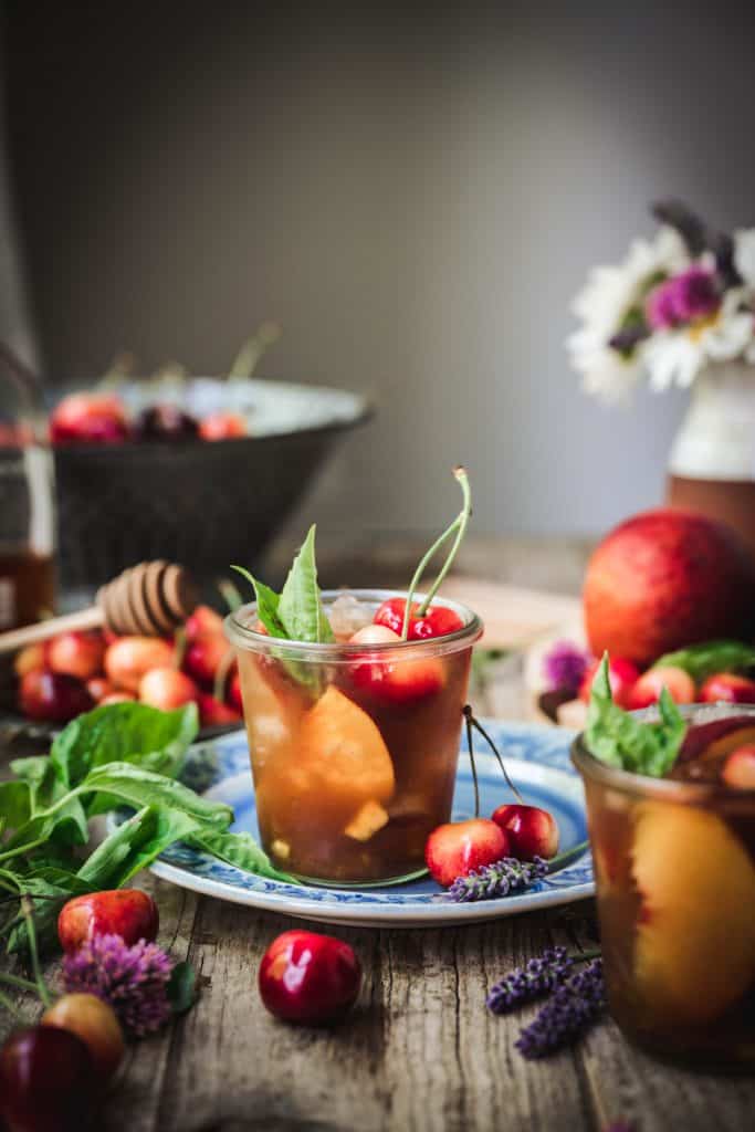 side view of bourbon peach smash cocktail on wood table