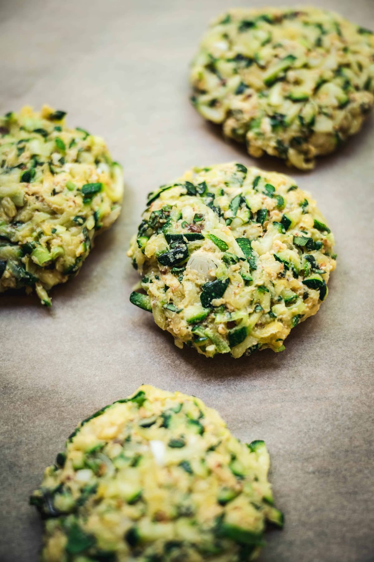 overhead of vegan zucchini fritters on parchment paper before they're cooked