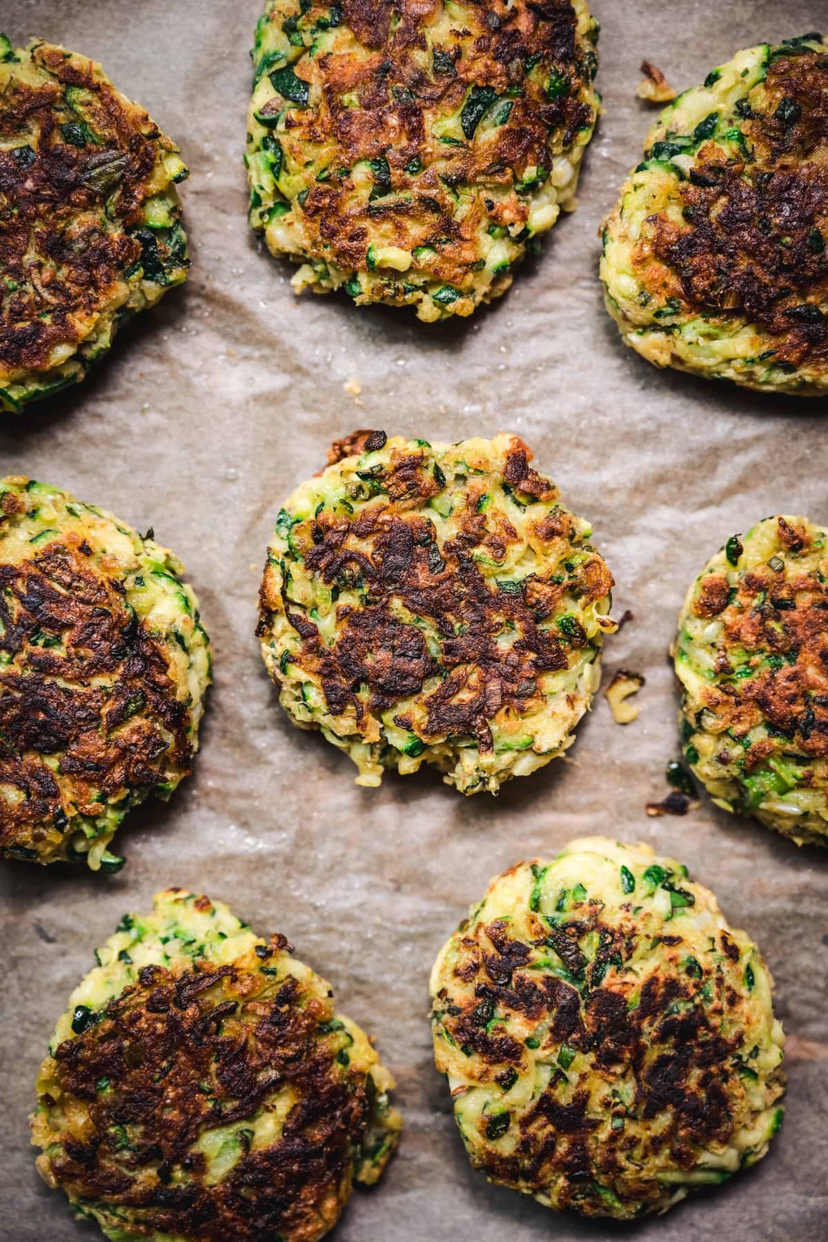 overhead of gluten free zucchini fritters on parchment after they're pan fried