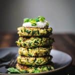 side view of a stack of gluten free zucchini fritters with vegan lemon cashew cream on top