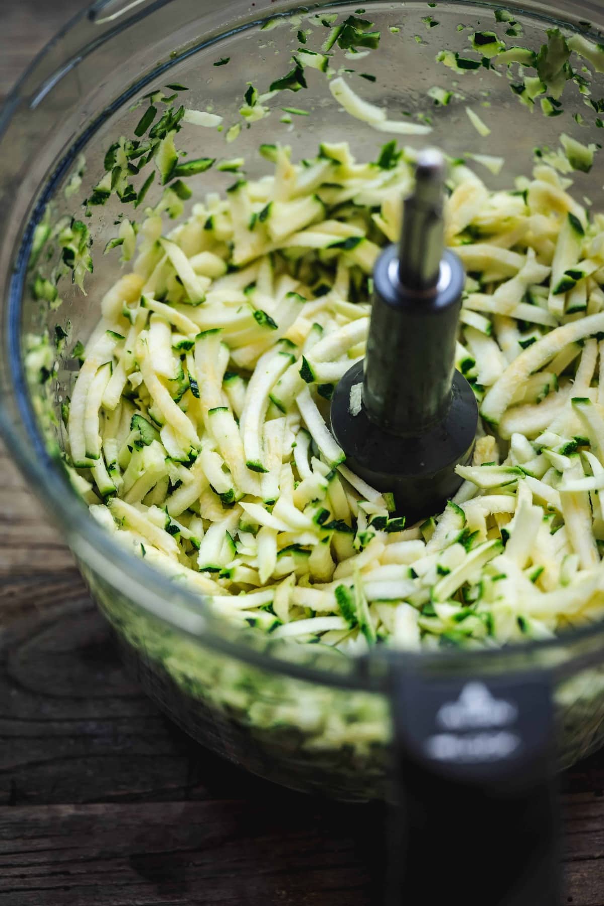 45 degree angle of shredded zucchini in a food processor