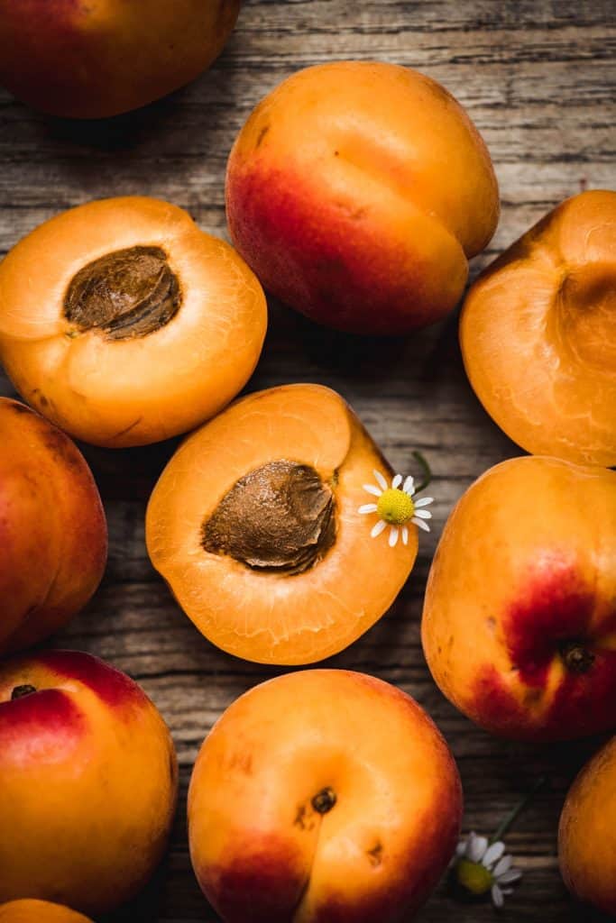 close up overhead view of beautiful fresh apricots with chamomile flowers on rustic wood background