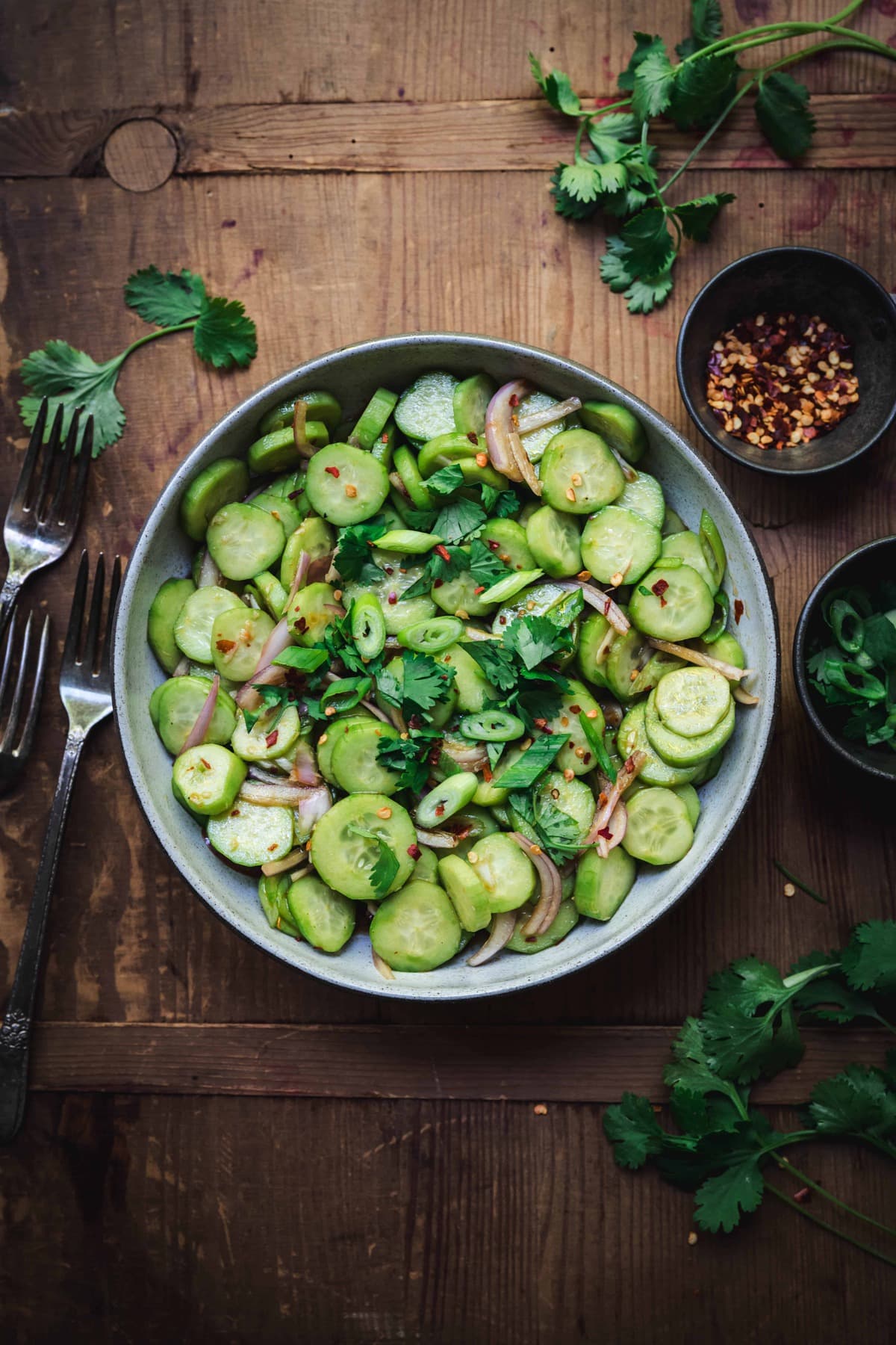overhead of asian cucumber salad in a bowl with fresh herbs