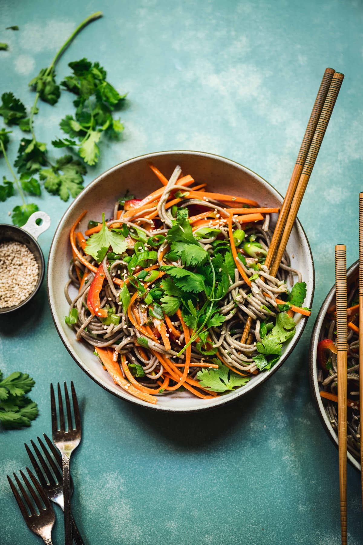 overhead of japanese soba noodle salad with citrus scallion dressing on a teal background