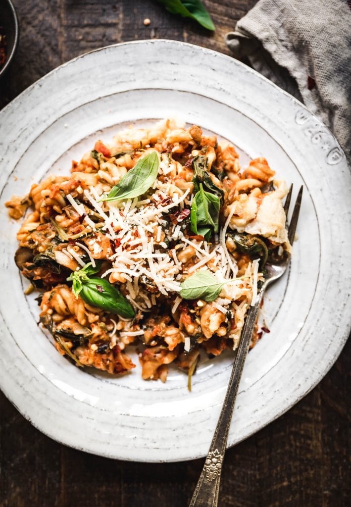 overhead view of healthy vegan gluten free pasta bake on a white plate with fork