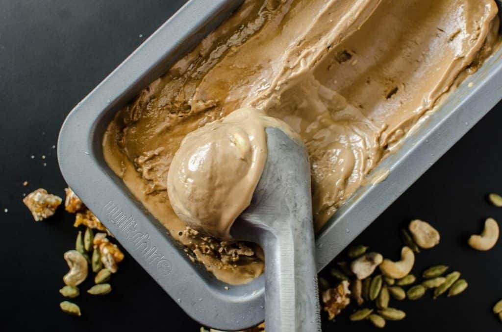 overhead of vegan caradmom spiced coconut ice cream in a tin with a scoop