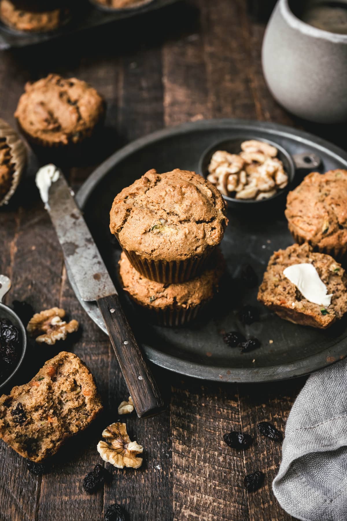 45 degree overhead of vegan gluten free carrot zucchini muffins with butter on a metal round tray