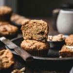 side view of a vegan gluten free zucchini carrot muffin sliced in half on a metal tray