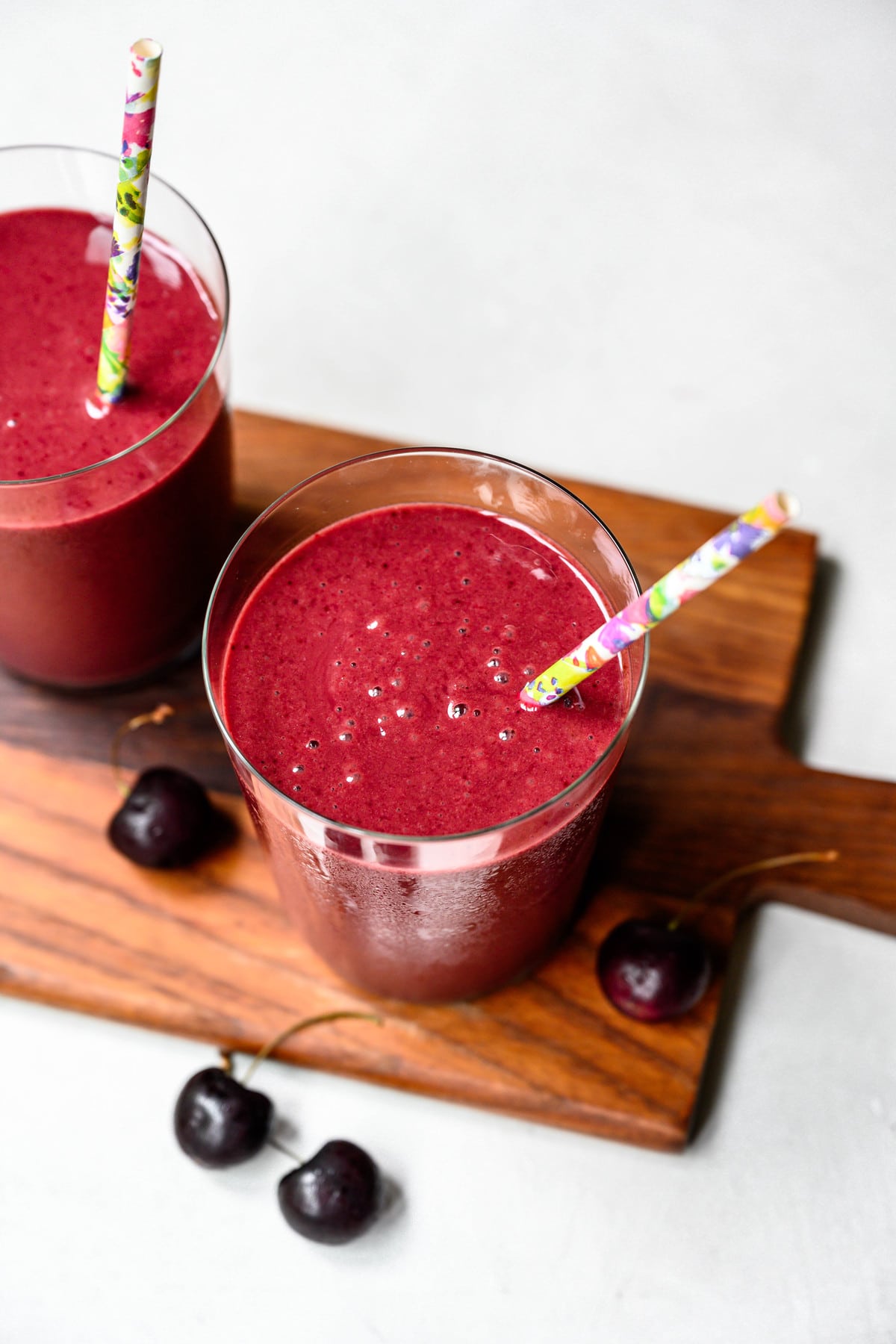 overhead of a tart cherry dark chocolate recovery smoothie in a glass with a paper straw