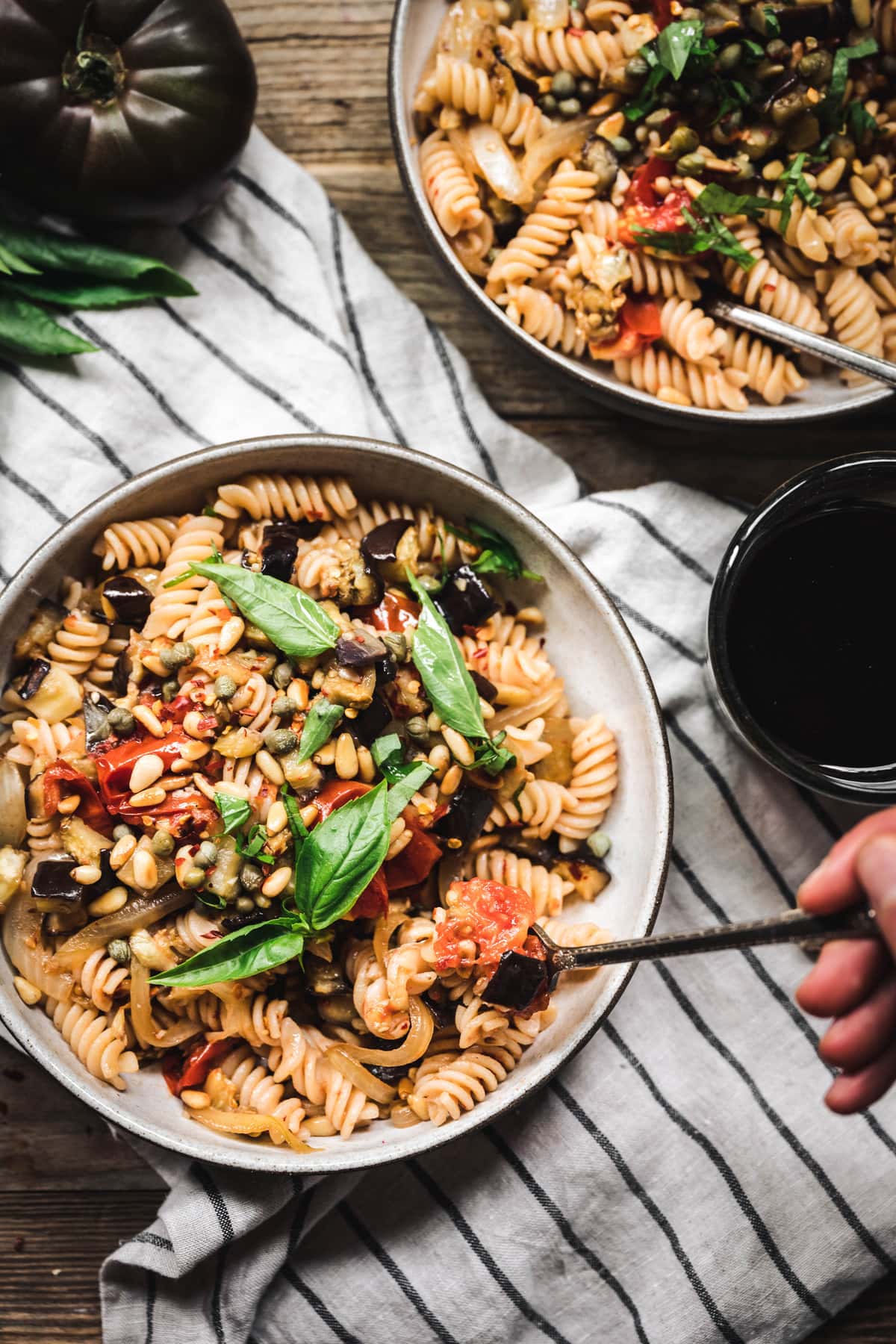 overhead of someone taking a bit of roasted eggplant tomato pasta 