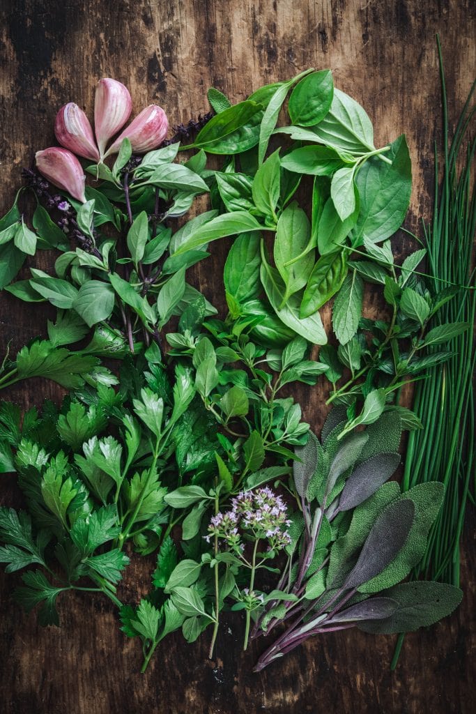 overead of a mixture of fresh herbs on a wooden background