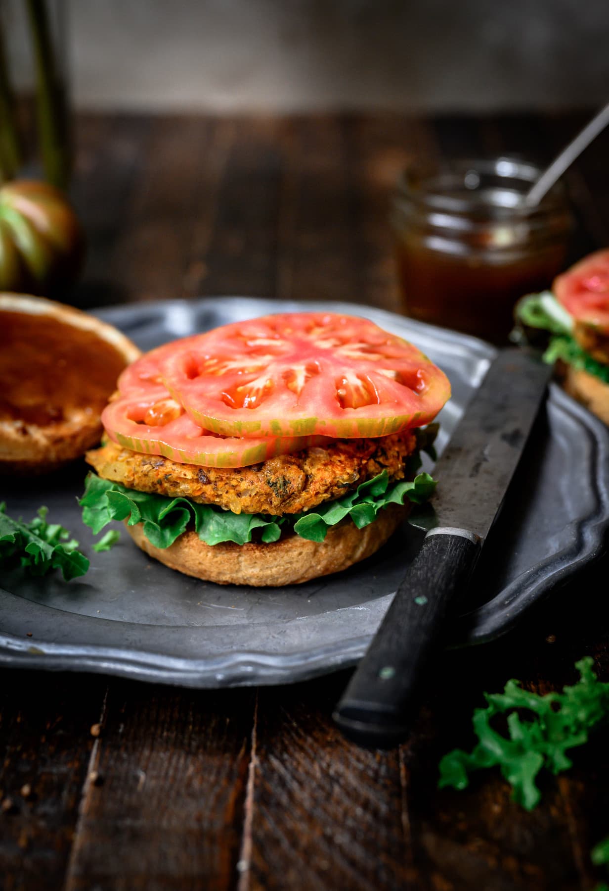 side view of open-faced indian veggie burger with tomatoes on top