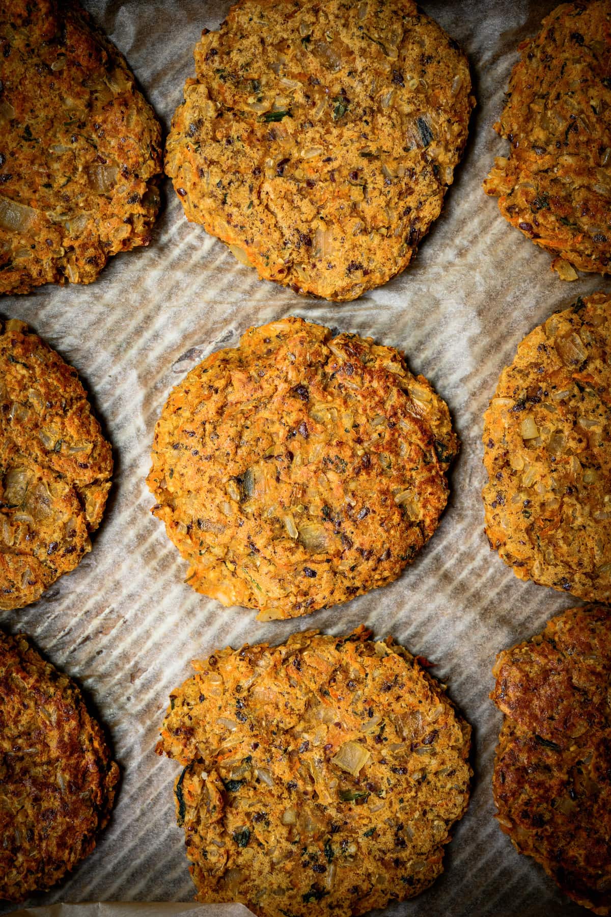 overhead view of cooked indian-spiced veggie burgers on parchment paper