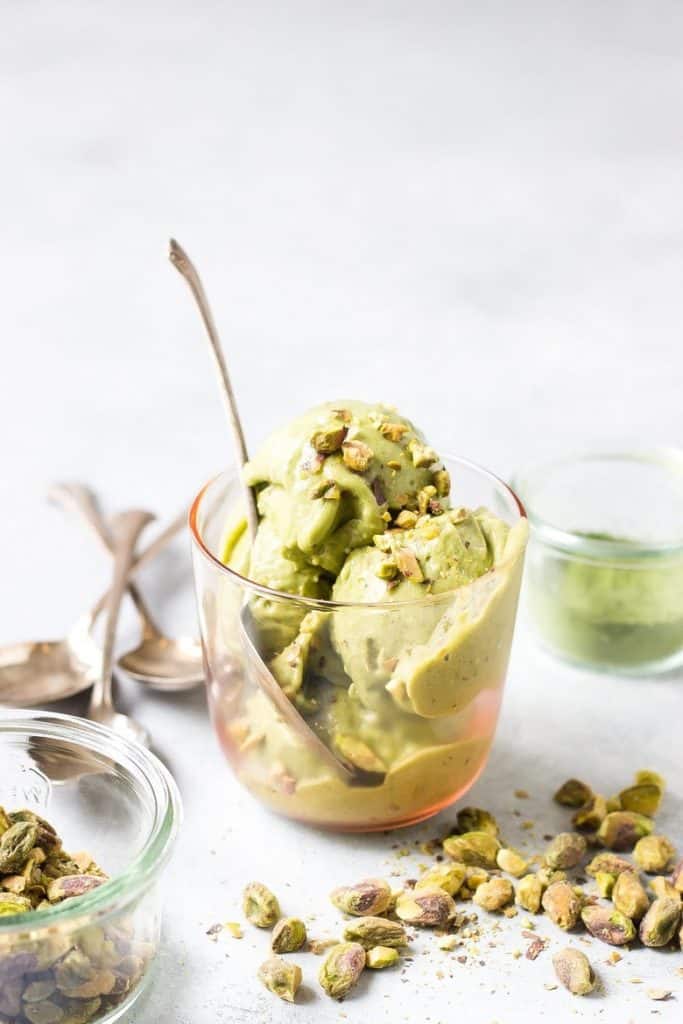 side view of a dish of vegan matcha pistachio ice cream with a spoon