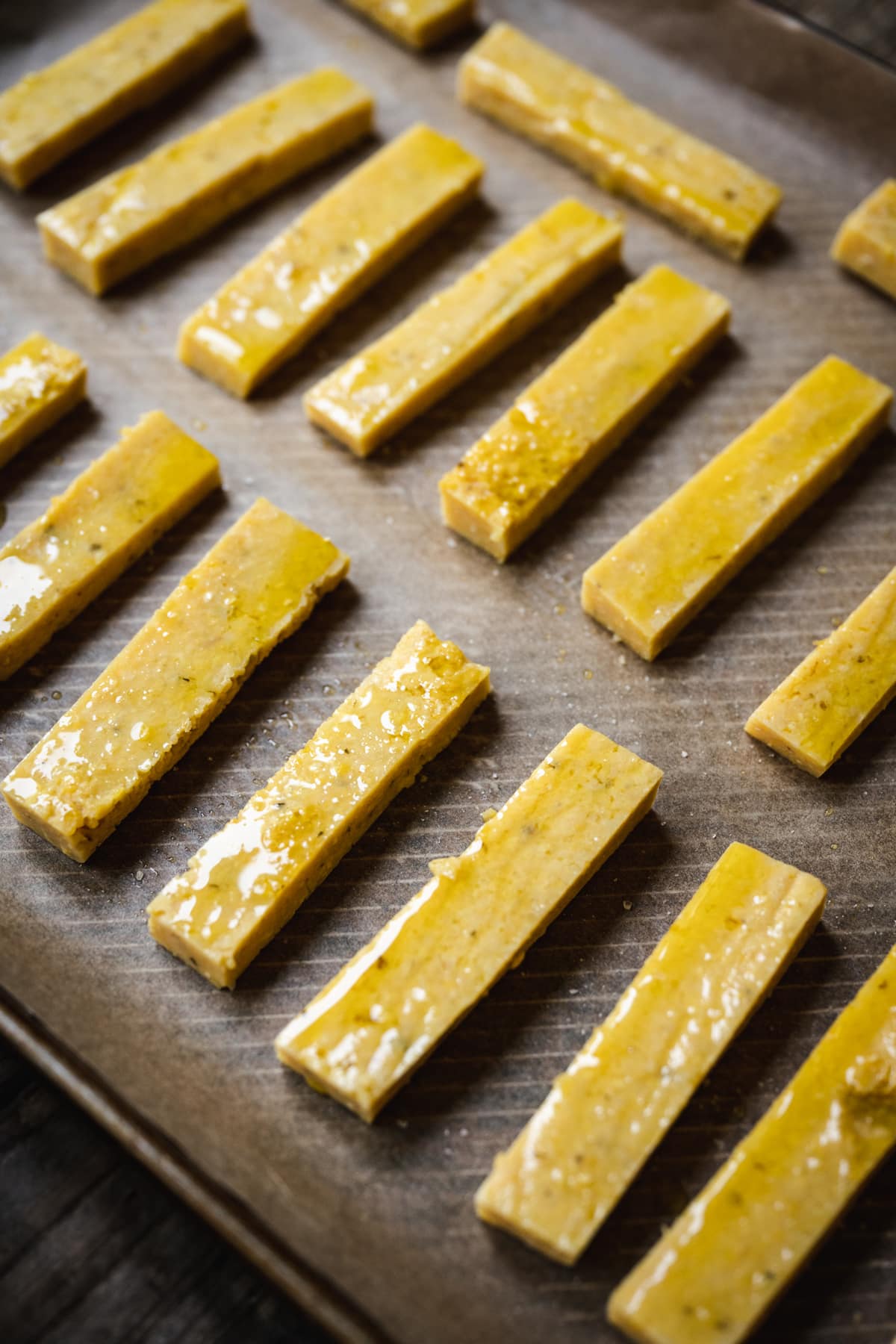 45 degree angle of polenta sticks on a baking dish before roasting