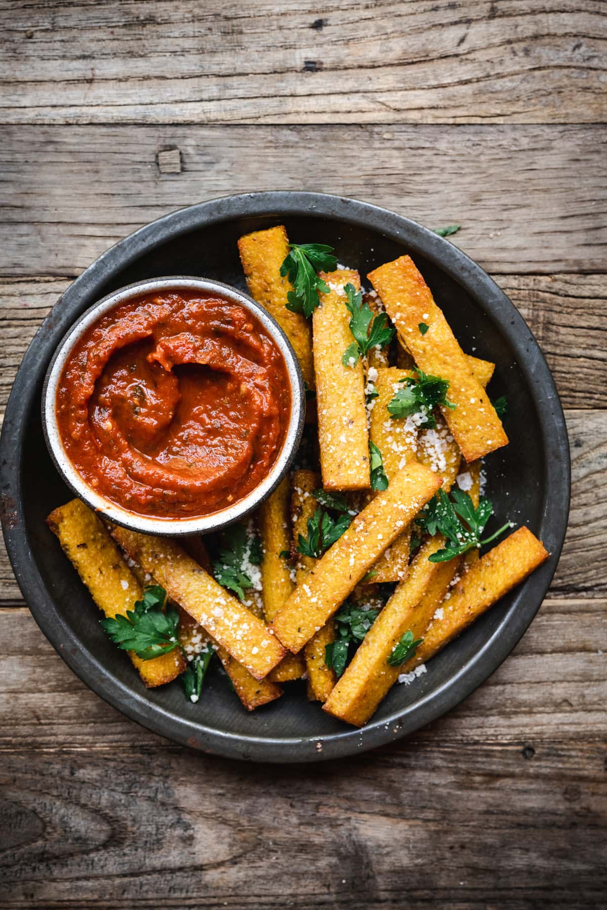 overhead of vegan polenta fries in a serving dish with marinara sauce