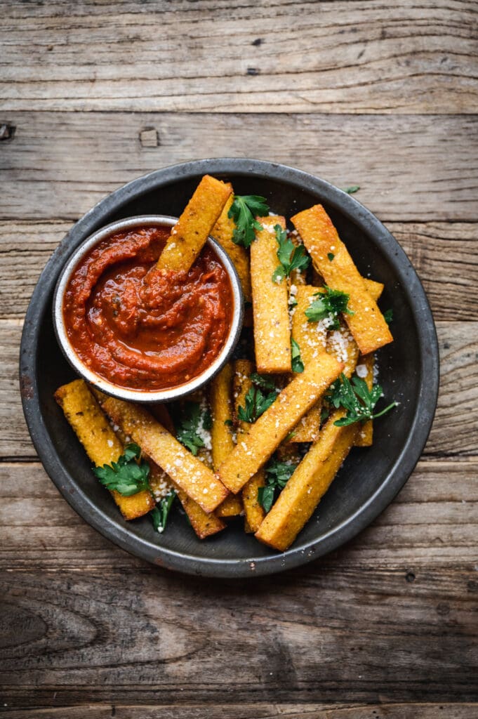 overhead of vegan polenta fries in homemade marinara sauce