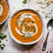 Roasted tomato soup in a bowl from above with a swirl of cream.