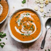 Roasted tomato soup in a bowl from above with a swirl of cream.