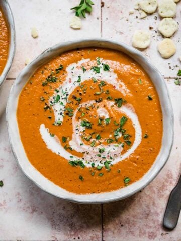 Roasted tomato soup in a bowl from above with a swirl of cream.