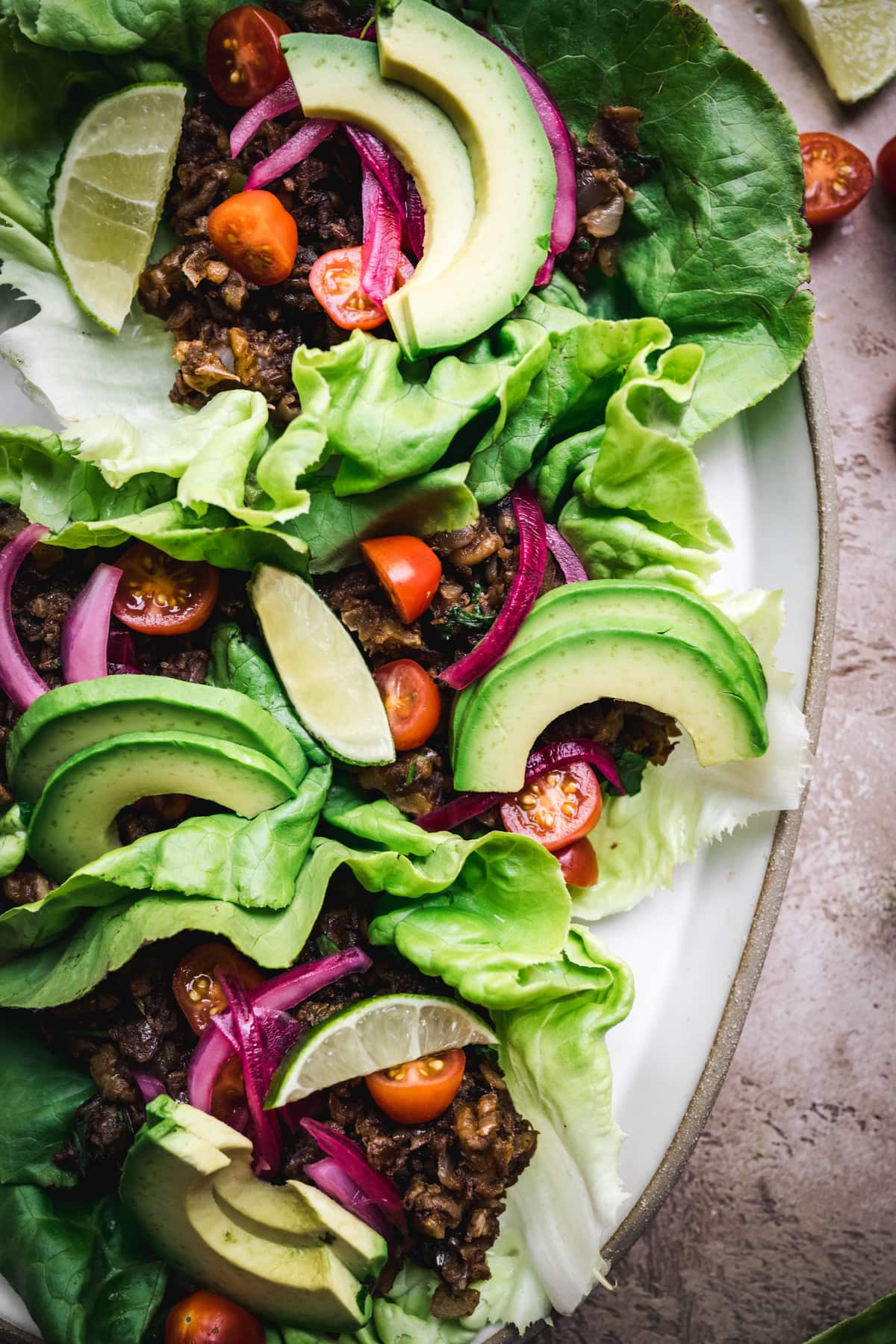 overhead of vegan taco lettuce wraps with sliced avocado on an oval platter