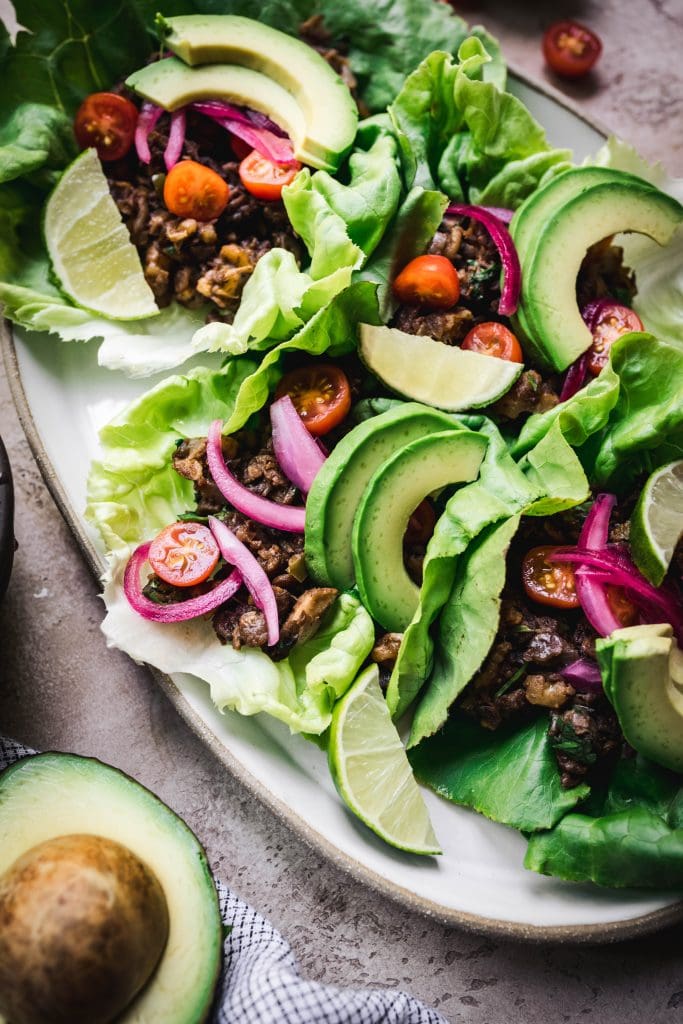 45 degree overhead of a platter of vegan taco lettuce wraps topped with avocado