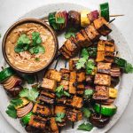 overhead of grilled tofu and vegetable kebabs with peanut sauce
