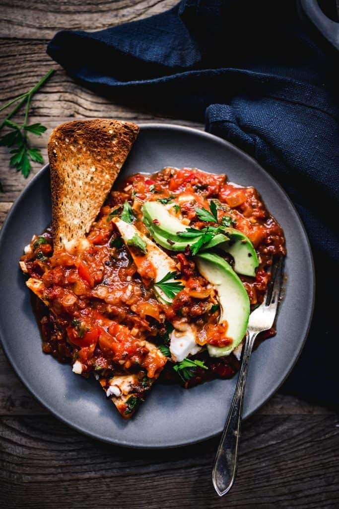 overhead of a slice of toast covered in vegan shakshuka on a blue plate