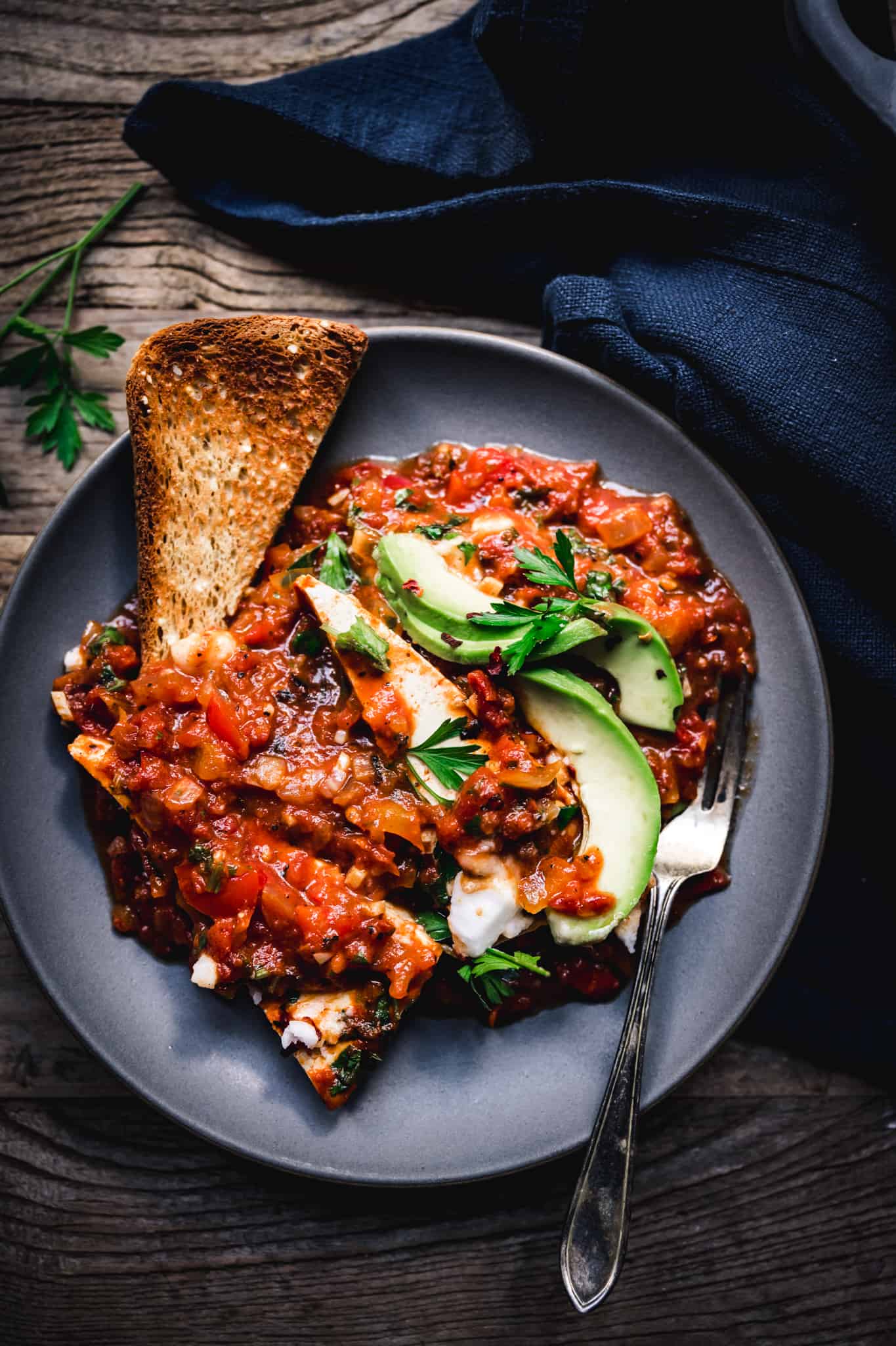 overhead of a slice of toast covered in vegan shakshuka on a blue plate