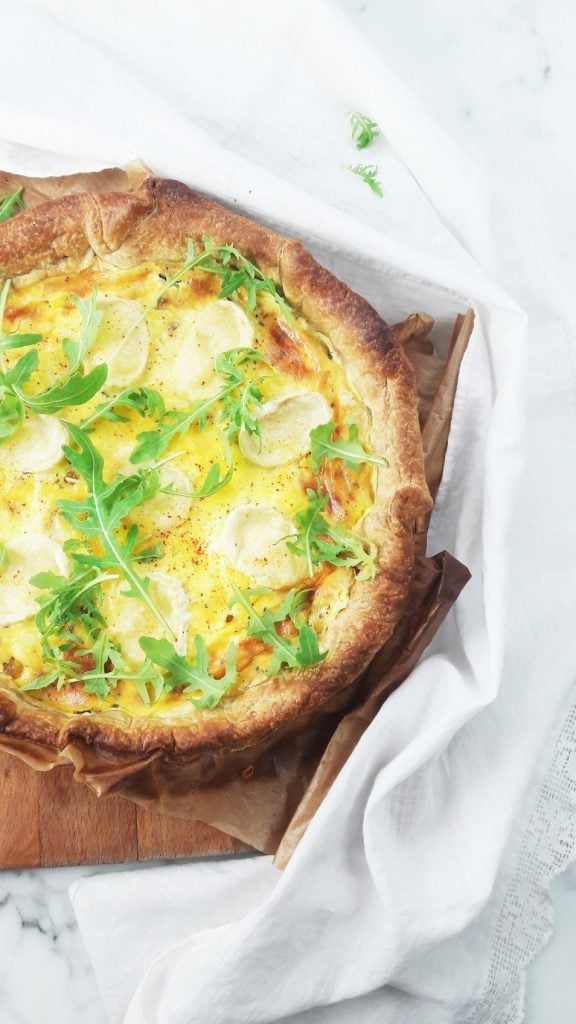 overhead of zucchini and goat cheese quiche with a white towel
