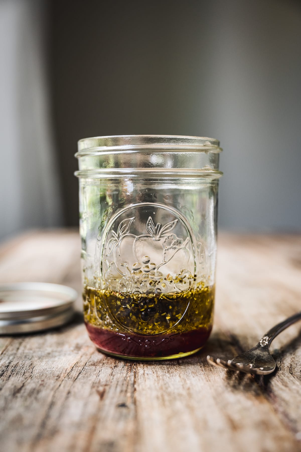 side view of herby vinaigrette in a mason jar