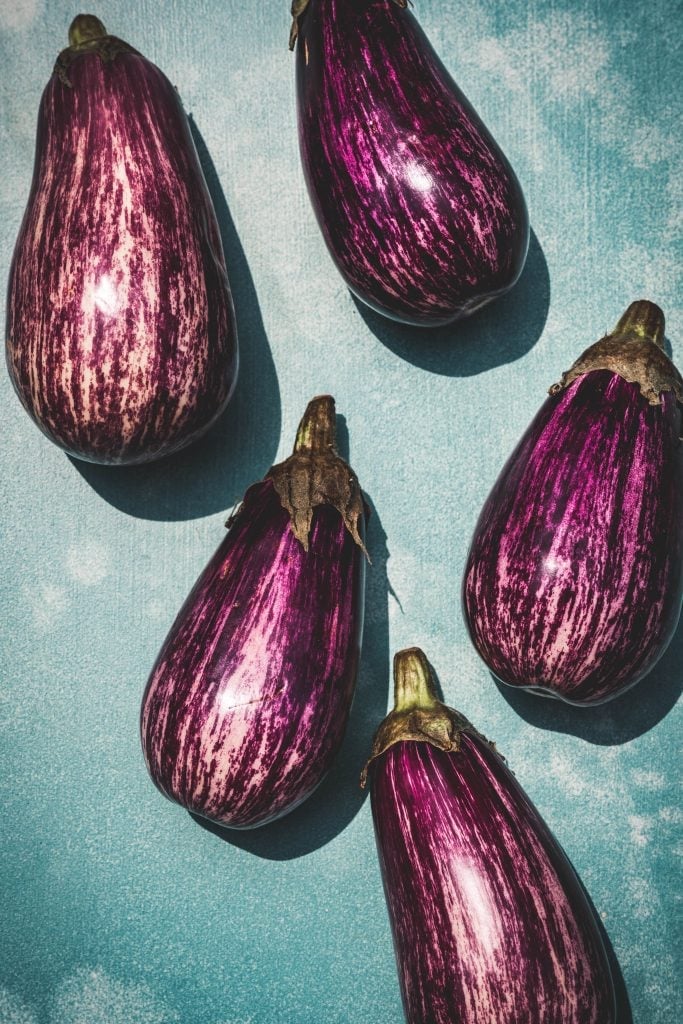 overhead of scicilian eggplants on a blue background