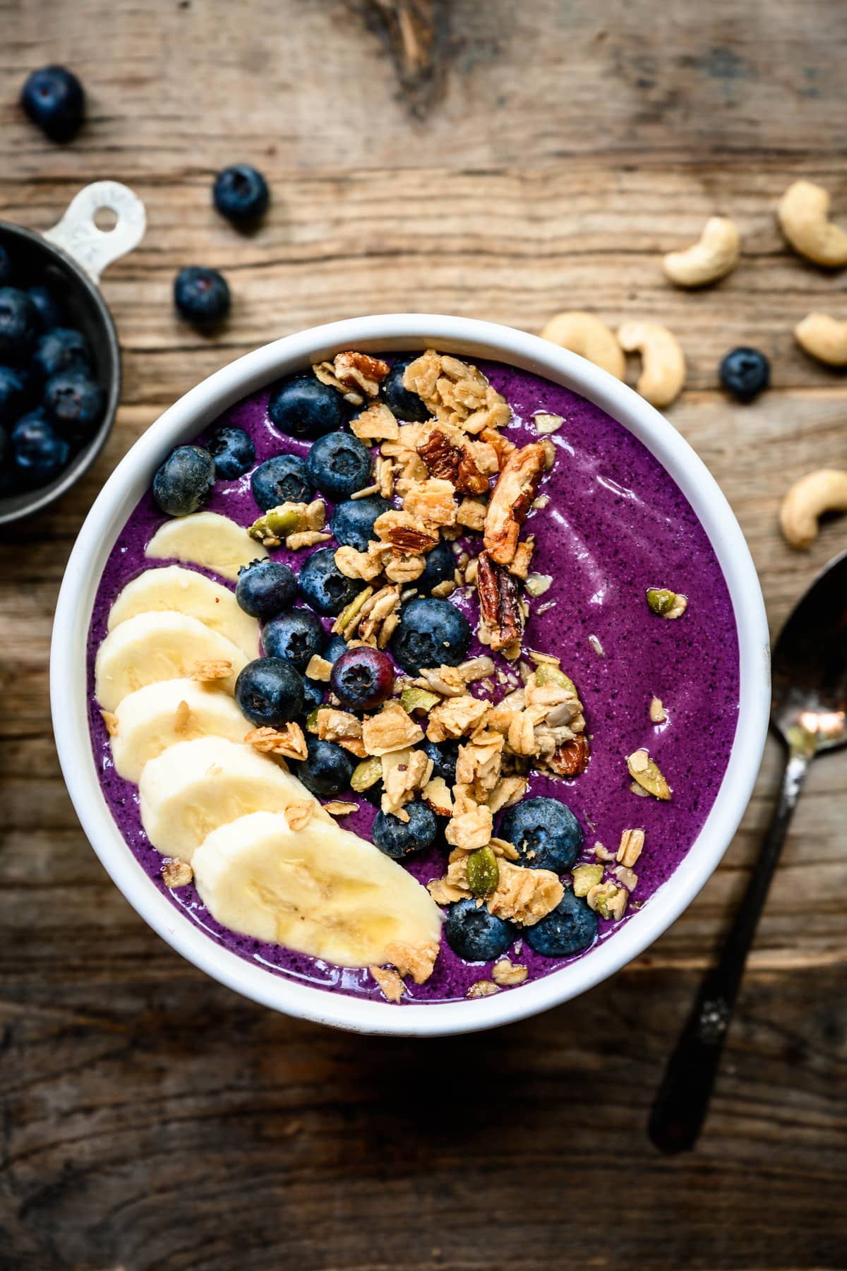 overhead of bluerry recovery smoothie bowl with banana and granola