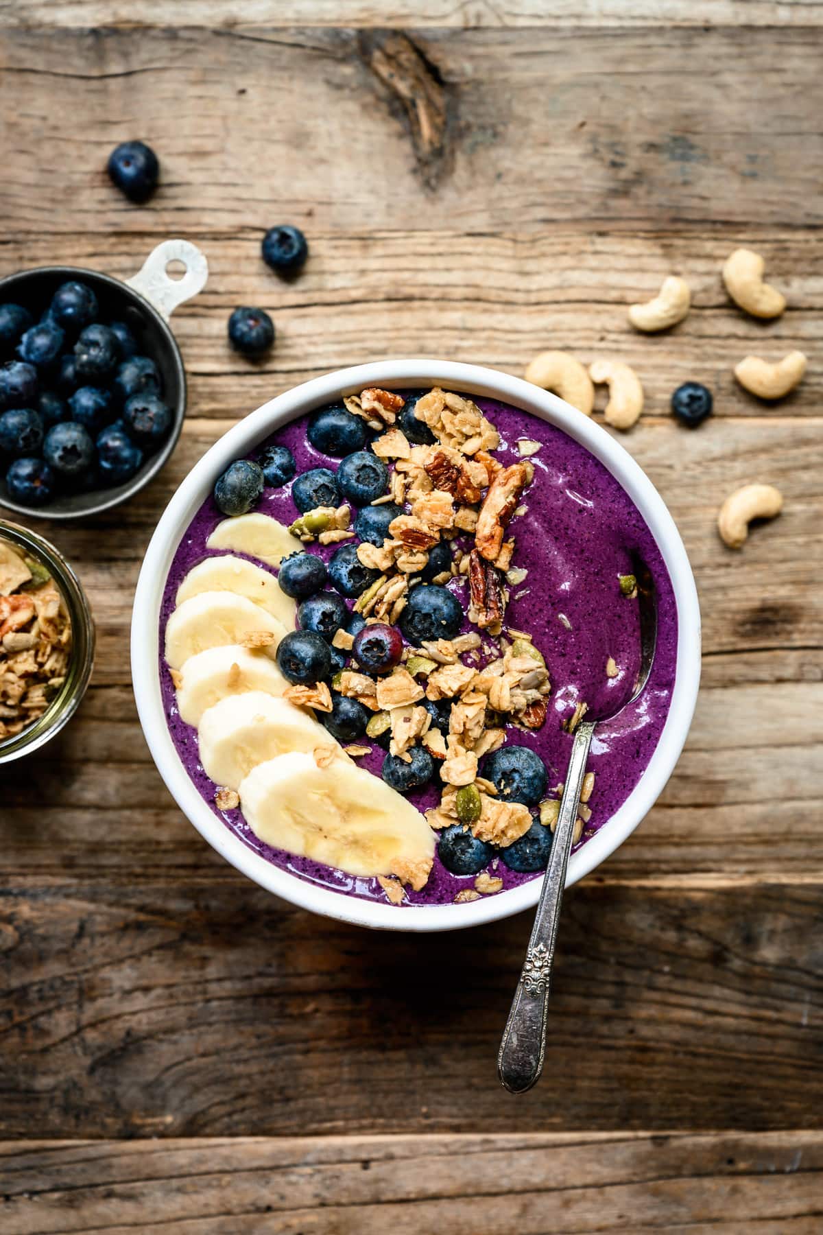 overhead of blueberry recovery smoothie bowl with banana, almond butter and granola