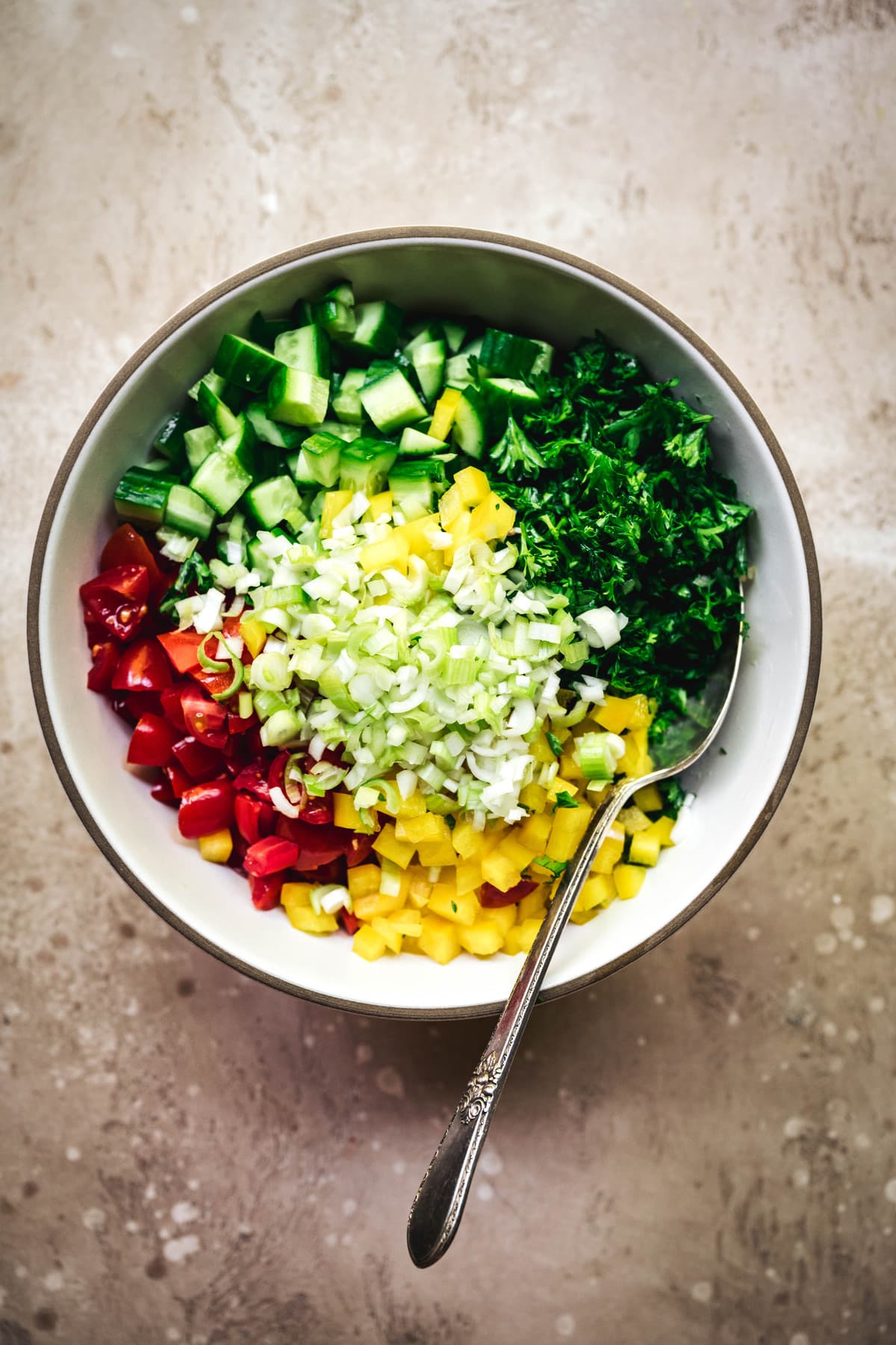 overhead view of diced vegetables in a bowl to make mediterranean stuffed avocados