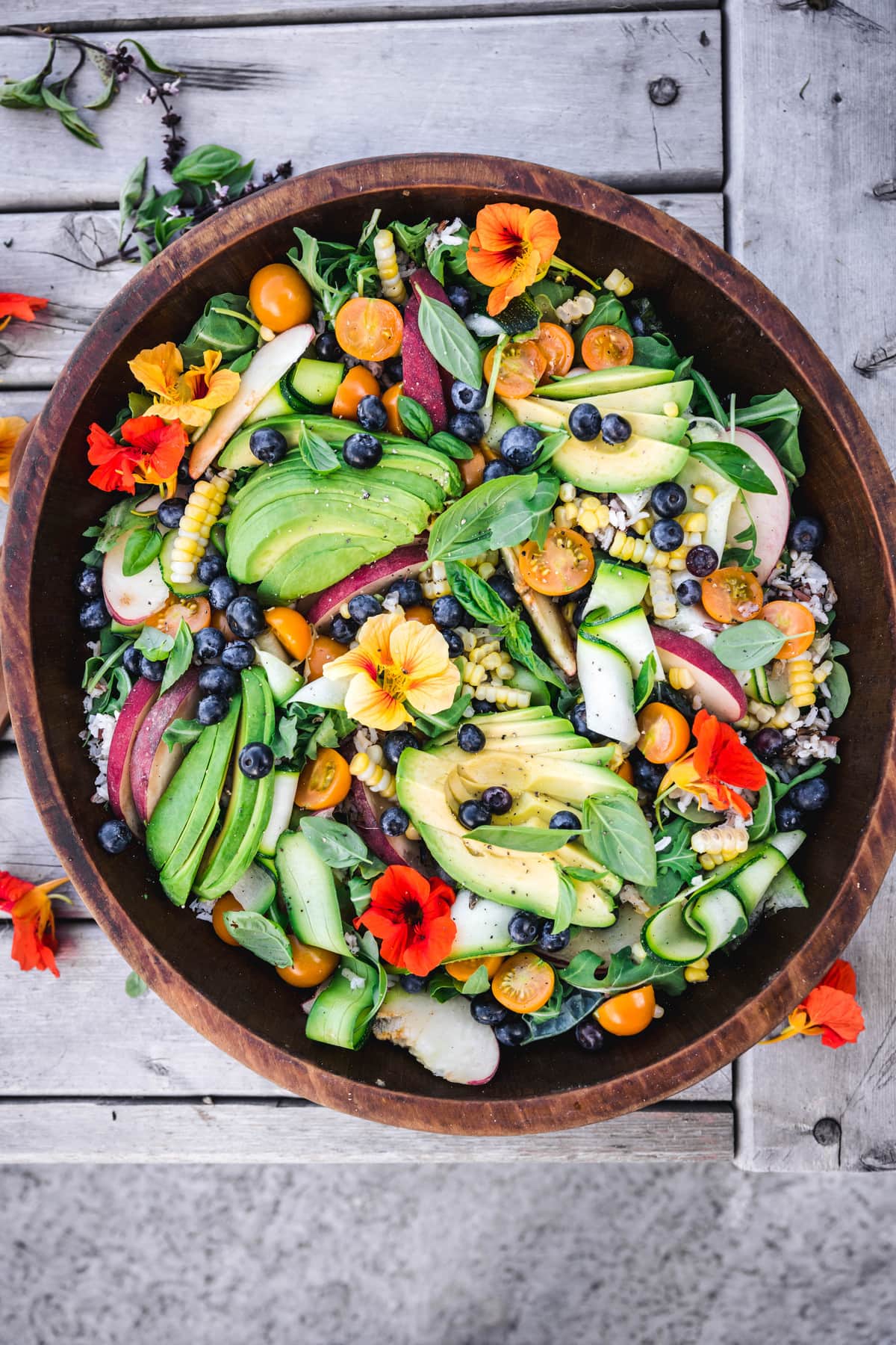 overhead of grain salad with summer vegetables on a picnic table outside