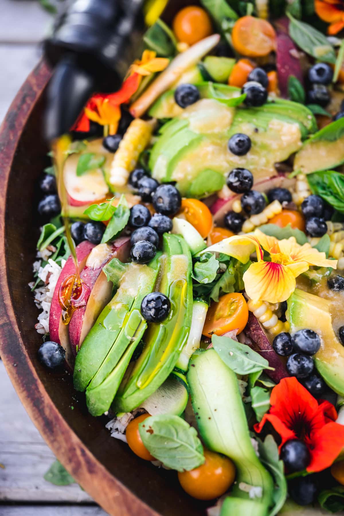 overhead closeup of summer grain salad with avocado and blueberries in a wooden serving bowl