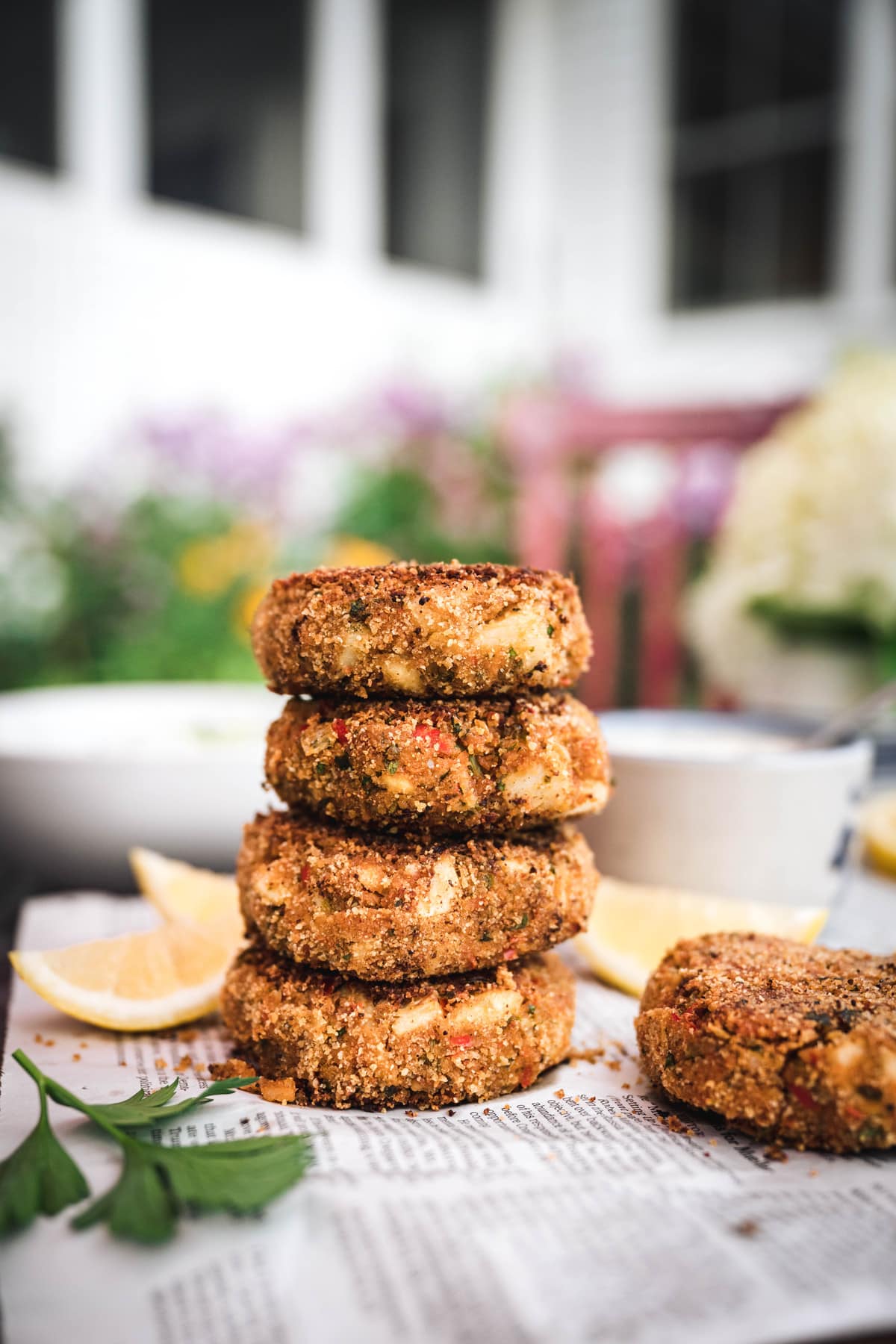 side view of a stack of four vegan crab cakes on newspaper