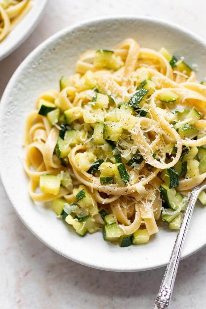 overhead of simple fresh zucchini pasta on a white plate from salt and lavendar