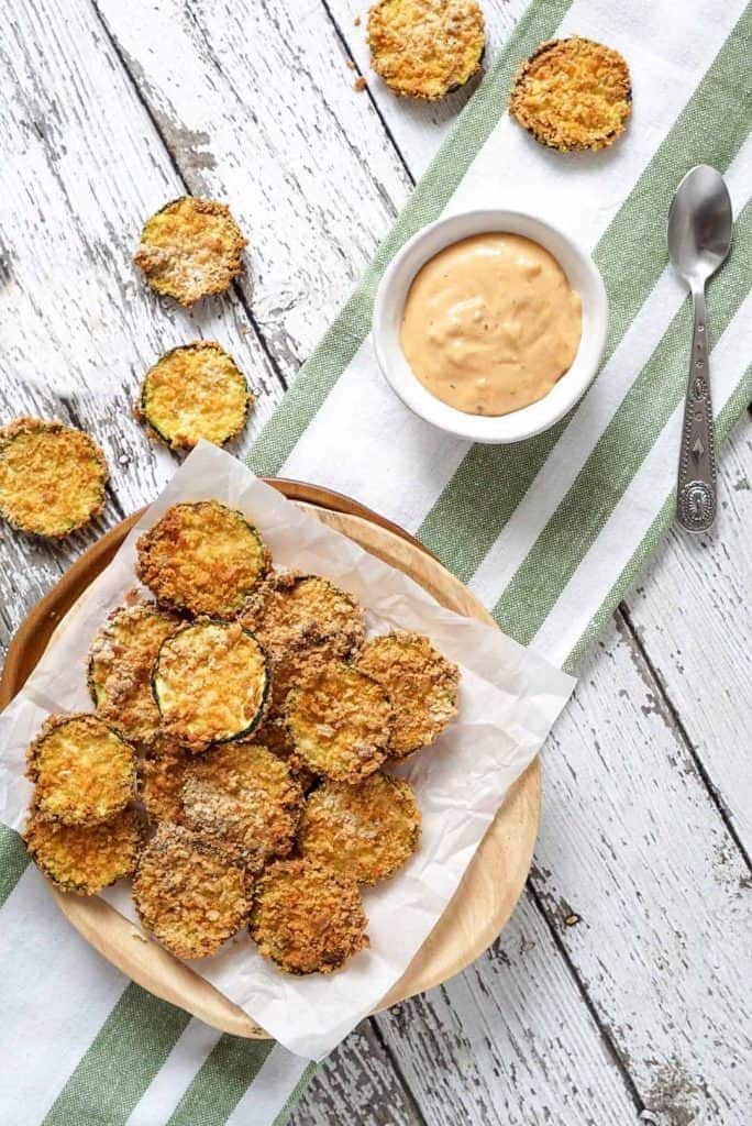 overhead of air fryer zucchini chips in a basket with dipping sauce