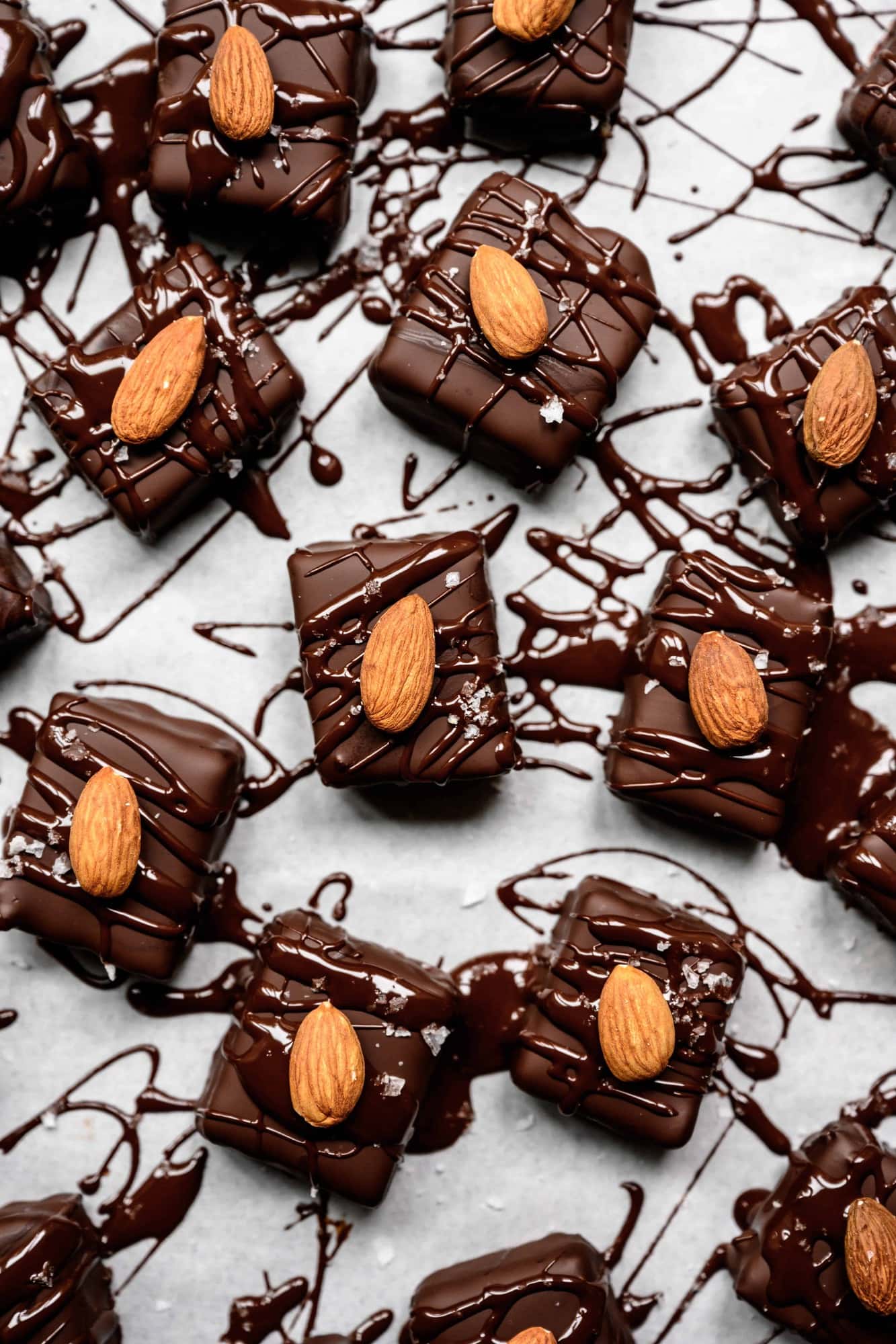 overhead of vegan almond joy bars on a white background with dark chocoalte splatter