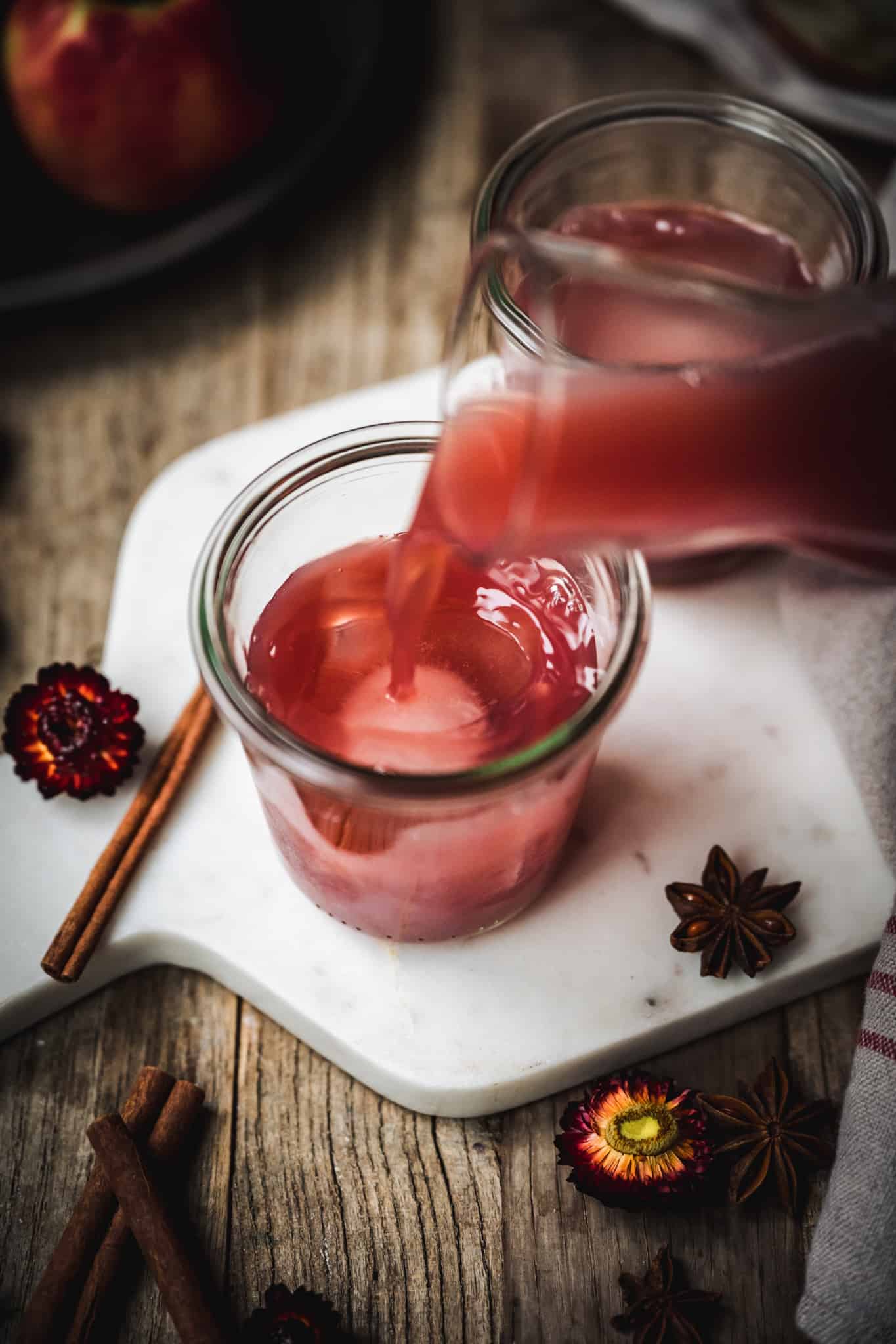 pouring fall cocktail into a glass over ice