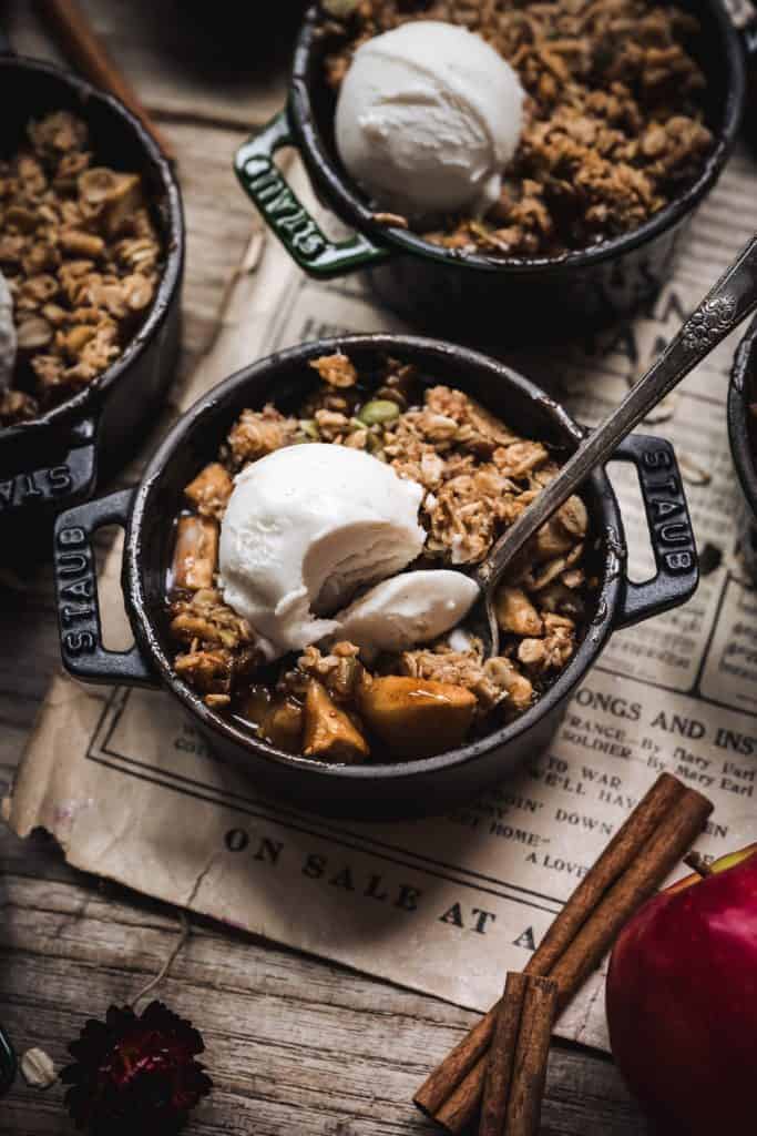 45 degree overhead of vegan apple crisp with vanilla ice cream on top and a bite taken out