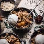 45 degree angle of vegan apple crisp in a mini cast iron pan with vanilla ice cream
