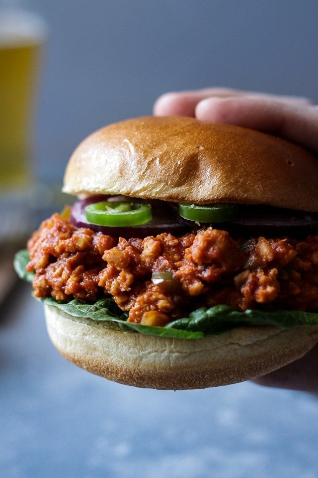 hand holding a vegan sloppy joe in a hamburger bun