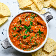 Close up view of cherry tomato salsa in a bowl with tortilla chips.