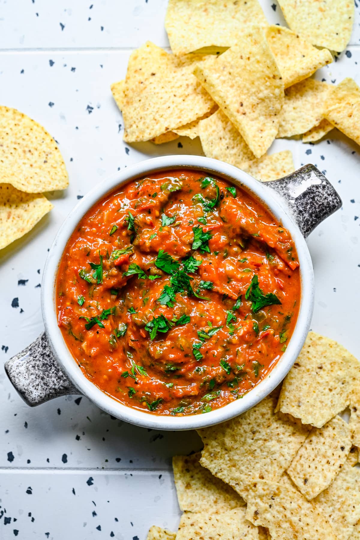 Close up view of cherry tomato salsa in a bowl with tortilla chips.