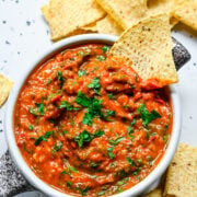 Close up view of cherry tomato salsa in a bowl with tortilla chips.