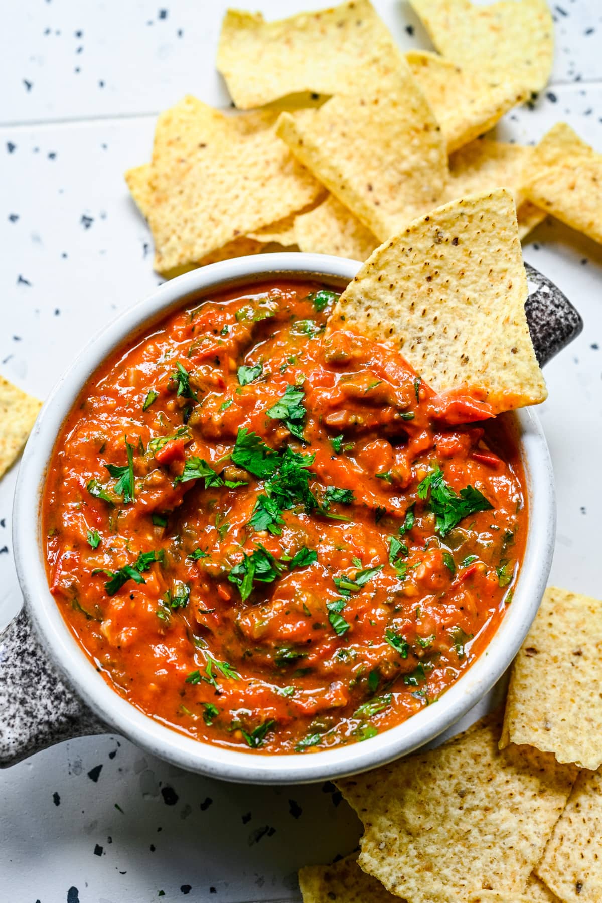 Close up view of cherry tomato salsa in a bowl with tortilla chips.